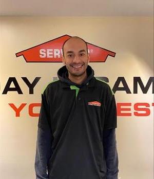 A tall younger man with thin hair on top and a slight beard, wearing a SERVPRO labeled golf shirt