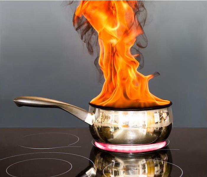  img src =”fire” alt = " stainless steel pot billowing with flames on an electric stove top ” >